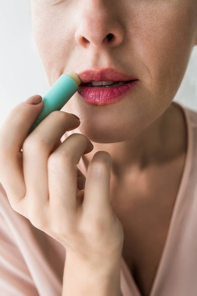 Close up of pretty woman applying lip balm. - Фото, зображення