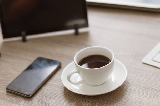 Xícara de café na mesa de madeira com tablet laptop e smartphone, espaço de cópia
 - Foto, Imagem