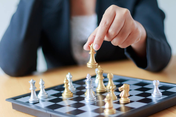 クローズ アップ ショットの手銀王を倒して黄金のチェスを移動ビジネスの女性のビジネス挑戦競争勝者と敗者のコンセプトの選択的な白と黒のチェス盤の上でチェスはチェス フィールドの浅い深さ王に集中 - 写真・画像