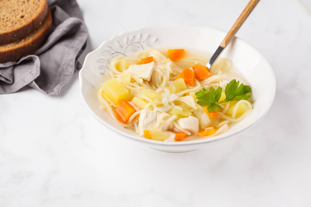 Chicken soup with noodles and vegetables in a white plate, white background. - Foto, imagen