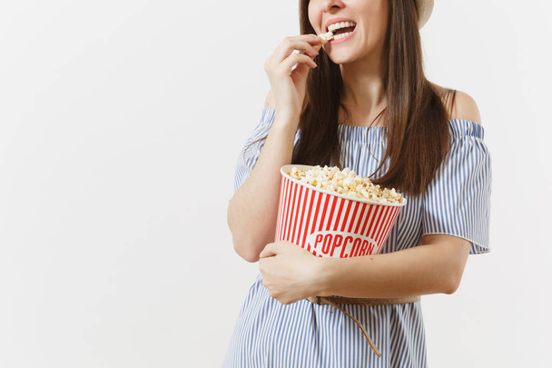 Обрізана жінка в блакитній сукні, капелюх дивиться фільм їсть попкорн з відра ізольовано на білому тлі. Люди, щирі емоції в кіно, концепція способу життя. Рекламна зона. Копіювати простір
 - Фото, зображення