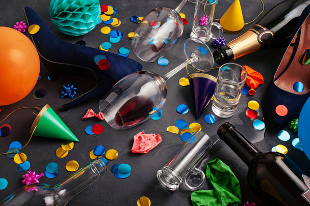 Top view laukaus juhlien jälkeen tyhjillä pulloilla, viinilasilla, tyttökengillä ja juhlatarvikkeilla
 - Valokuva, kuva