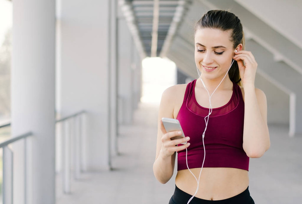 Portrait of an active young girl browsing music in preparation for her workout - Фото, изображение