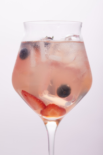 close up shot of glass of lemonade with ice cubes, strawberries and blueberries isolated on grey background  - Foto, imagen