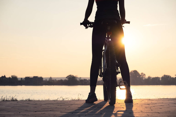 Silhouette di una ragazza vicino al mare in bicicletta. Sport e concetto di vita attiva
 - Foto, immagini
