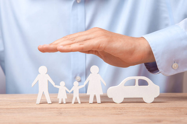 Familien- und Autoversicherung. Mann im Hemd deckt seine Familie mit Vater, Mutter, Sohn und Tochter und Auto ab - Foto, Bild