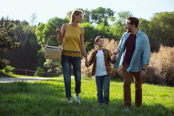 Happy family. Cheerful blond mother holding a basket and having a walk with her family - Фото, зображення