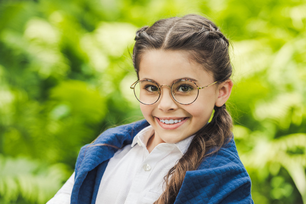 close-up portrait of smiling schoolgirl in white shirt and jumper over shoulders looking at camera - Fotografie, Obrázek