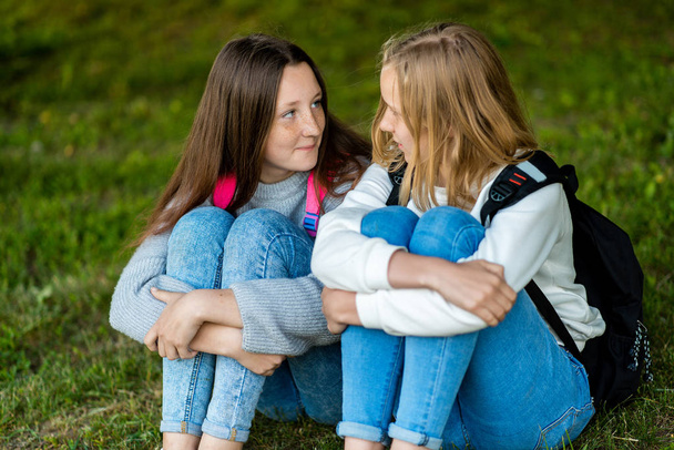 Two teenage girl. Summer in nature. They are sitting on grass. Communicate with each other. He talks intimate conversation. Best friends. Privacy from adults. - Foto, Bild