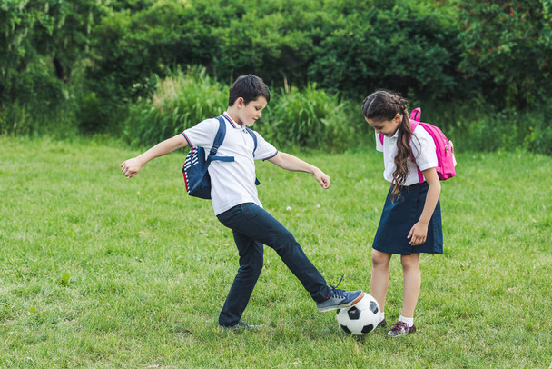 щасливі школярі грають у футбол разом на лузі в парку
 - Фото, зображення