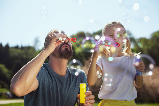 Content father blowing bubbles with his daughter - Φωτογραφία, εικόνα