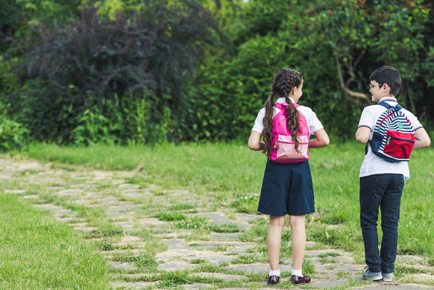 вид сзади школьников, идущих по тропинке в парке вместе
 - Фото, изображение
