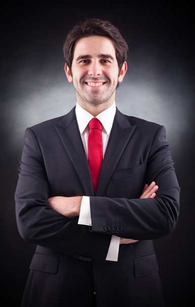 Friendly handsome businessman standing on black background - Foto, afbeelding
