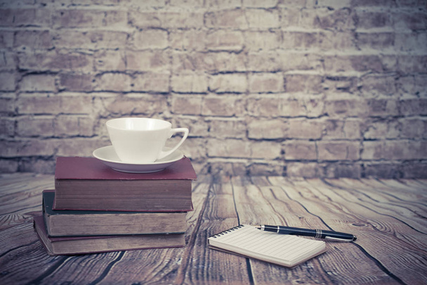 coffee cup on old book set up on wood table and old brick wall. - Photo, image