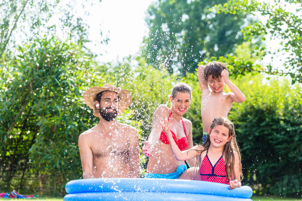 Rodzina chłodzenia wodą w basenie w ogrodzie  - Zdjęcie, obraz