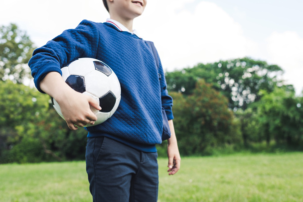 芝生のフィールドでサッカー ボールを保持している子供のショットをトリミング - 写真・画像