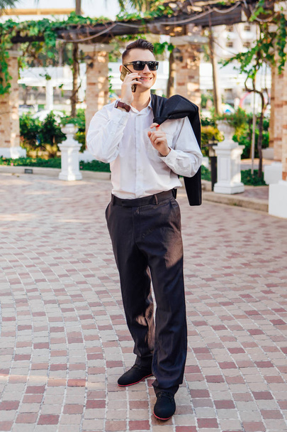 Young businessman talking on his phone outdoors in a tropical country - Foto, Imagen