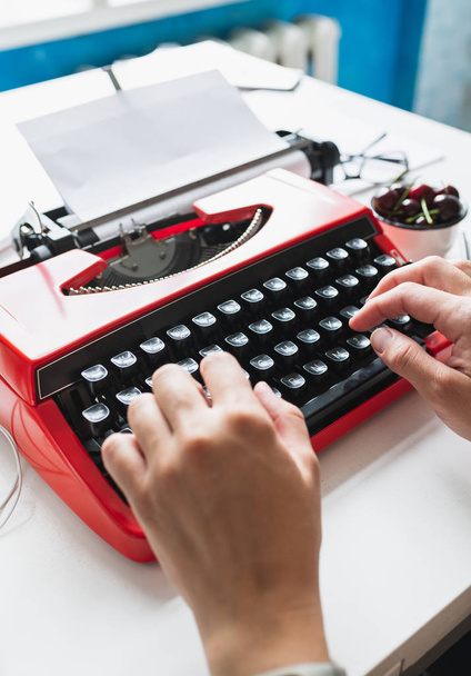 Mulher mão trabalhando com vermelho brilhante máquina de escrever vintage
 - Foto, Imagem