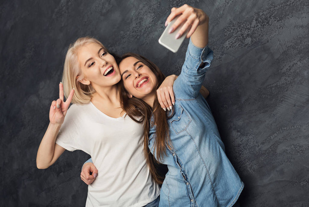 Dvě šťastné ženy užívající selfie na studio pozadí - Fotografie, Obrázek