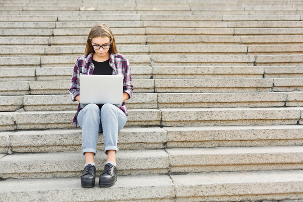 Serious student sitting on stairs using laptop - Photo, Image