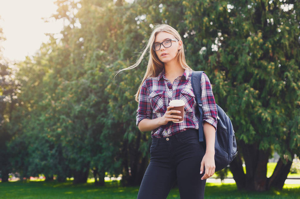 Student girl standing with coffee cup outdoors - Фото, изображение