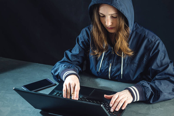 Dziewczyna haker używa laptopa do hack system. Kradzież danych osobowych. Tworzenie i infekcji złośliwego wirusa. Pojęcie cyberprzestępczości i hacking urządzeń elektronicznych - Zdjęcie, obraz