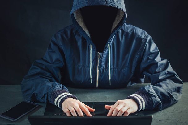 Anonieme hacker programmeur maakt gebruik van een laptop hack van het systeem. Het stelen van persoonlijke gegevens. Creatie en infectie van schadelijke virus. Het concept van cybercriminaliteit en hacking elektronische apparaten - Foto, afbeelding