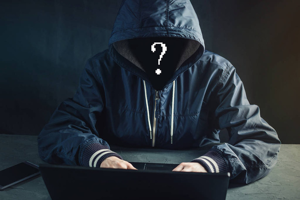 Anonymous hacker programmer uses a laptop to hack the system. Stealing personal data. Creation and infection of malicious virus. The concept of cyber crime and hacking electronic devices - Photo, Image