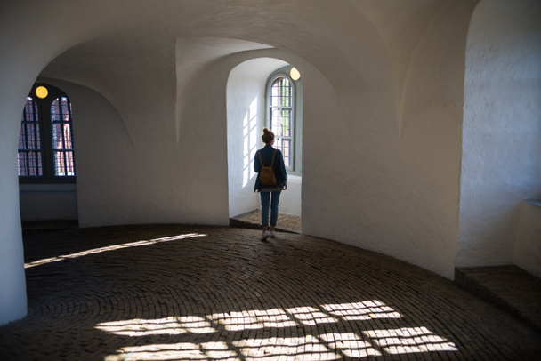 vista trasera de la joven mujer de pie en un hermoso edificio histórico y mirando a la ventana, Interior de la Torre Redonda
  - Foto, imagen