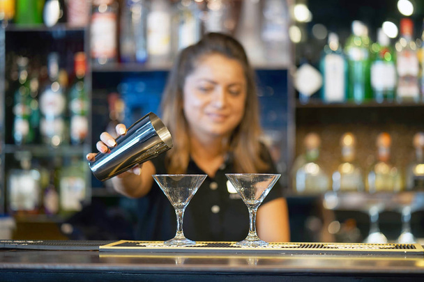 Profesjonalny barman dziewczyna nalewa odświeżające koktajle do klientów w hotelowym barze. Pojęcie usługi. Zaangażownie szkła. - Zdjęcie, obraz