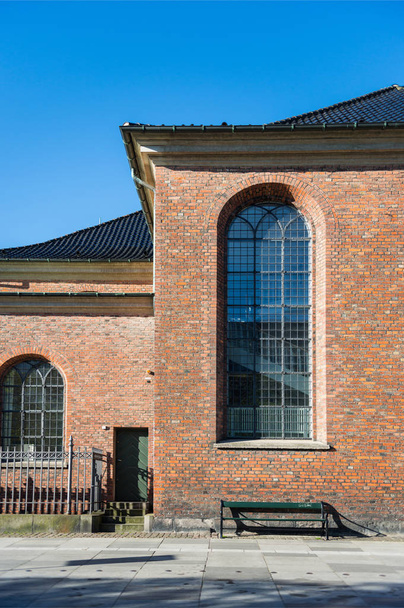 晴れた日、コペンハーゲン、デンマークで大きな窓と空ベンチのきちんとした茶色建物 - 写真・画像