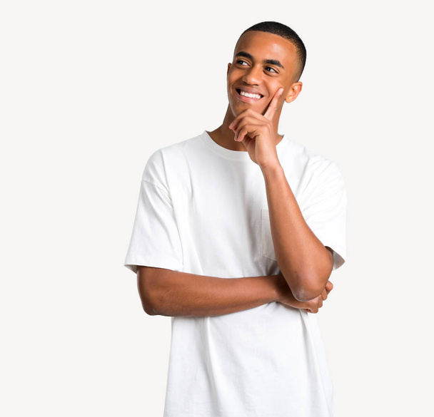 Young african american man standing and thinking an idea while looking up on isolated background - Photo, Image