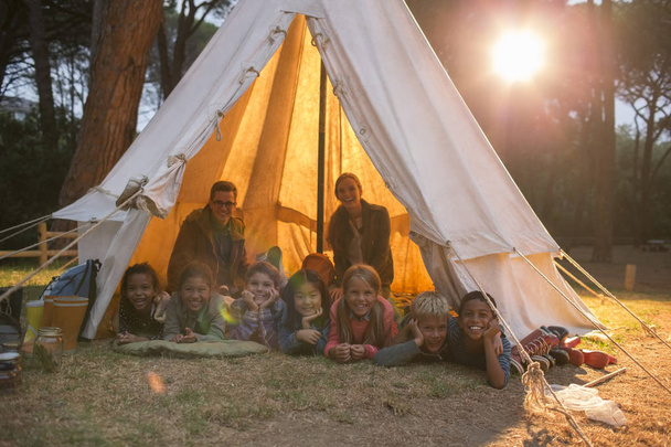 Students and teachers smiling in teepee at campsite - Photo, Image