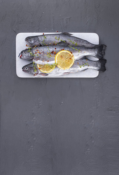 Raw fish. Trout with lemon and spices on a white stone board. Gray background. Free space for text. copy space. flat lay - Φωτογραφία, εικόνα