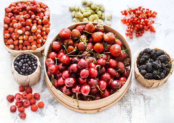 composition of different fruits in baskets on a light wooden background, concept of healthy nutrition and vitamins - Photo, Image