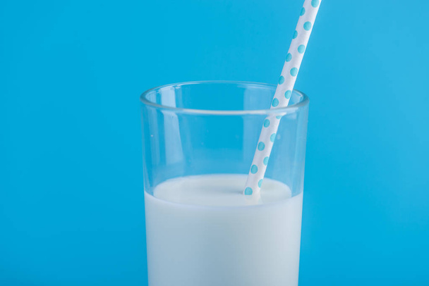 Стакан свежего молока с соломой на синем фоне. Красочный минимализм. Концепция здоровых молочных продуктов с кальцием
 - Фото, изображение