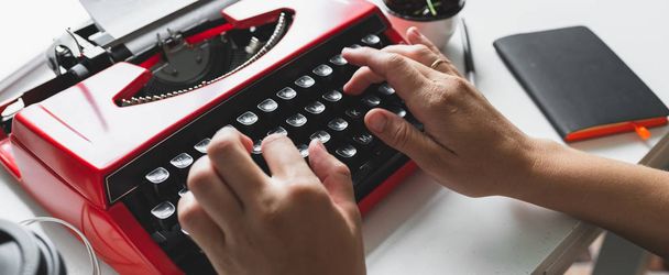 明るい赤ヴィンテージ タイプライターを扱う女性の手 - 写真・画像
