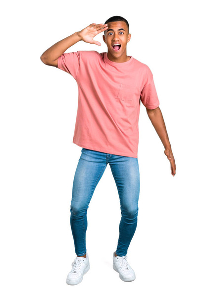 Standing young african american man with surprise and shocked facial expression. Gaping because can not believe what is happening on isolated white background - Fotó, kép