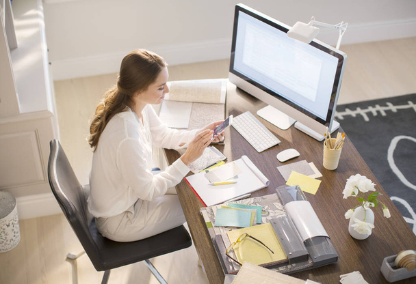 Дизайнер интерьеров пишет смс на мобильный телефон на рабочем столе в офисе
 - Фото, изображение