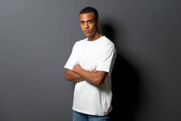 腕を組んでの灰色の壁背景に若いアフリカ系アメリカ人 - 写真・画像
