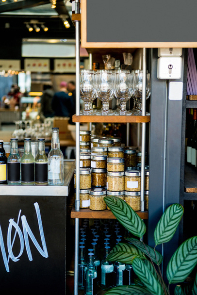 селективная направленность полок с банками с зерновыми, стаканами и бутылками в кафе
  - Фото, изображение