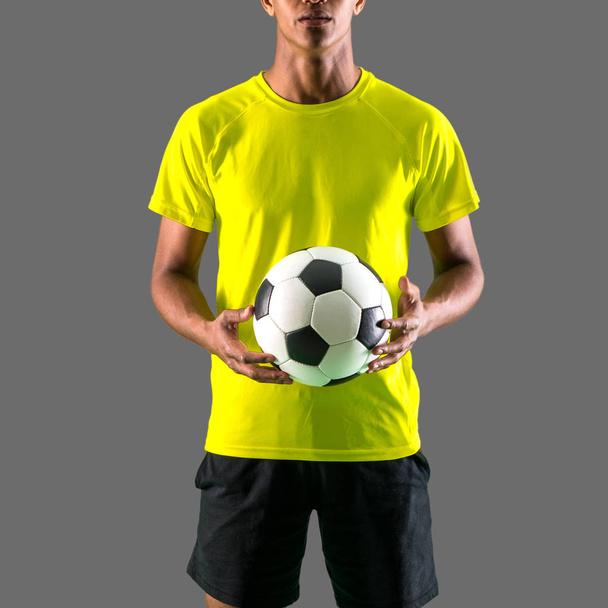 Soccer player man with dark skinned playing catching a ball with his hands on dark background - Foto, Imagem