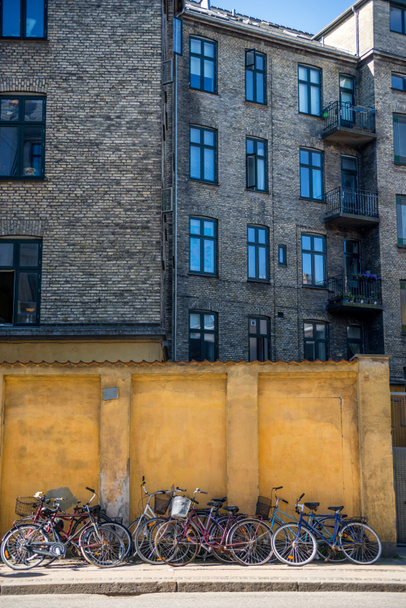 building and parked bicycles near yellow stone wall in Copenhagen, Denmark - Zdjęcie, obraz