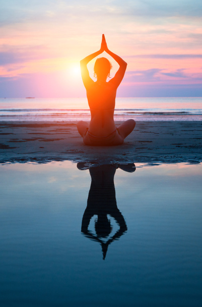 junge Frau praktiziert Yoga am Strand bei Sonnenuntergang - Foto, Bild