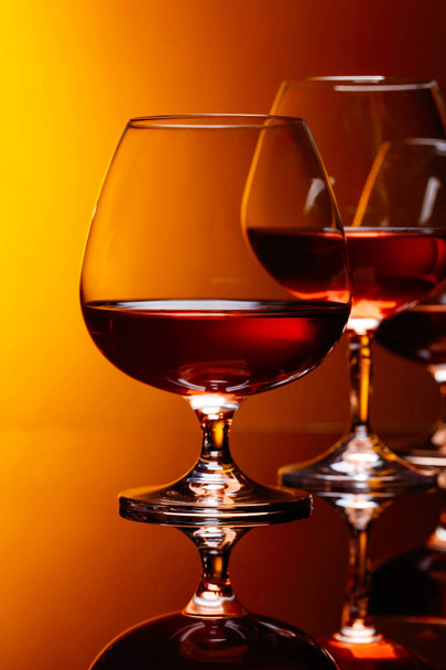 Glasses of brandy on a black reflective background. - Photo, Image