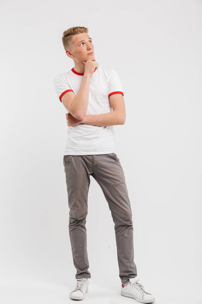 Full length portrait of a pensive teenage boy looking away isolated over white background - Foto, immagini