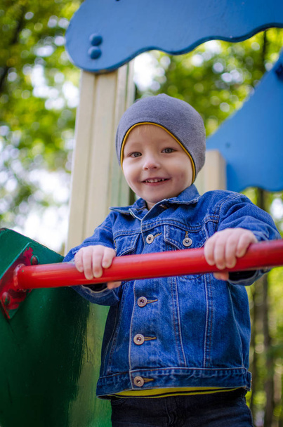 Gelukkig glimlachend jongetje plezier op speelplaats in het najaar. Schattige jongen kind buiten spelen op de speelplaats. - Foto, afbeelding