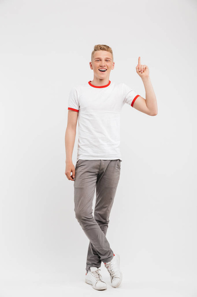 Full length portrait of a smiling teenage boy pointing up at copy space isolated over white background - Фото, зображення