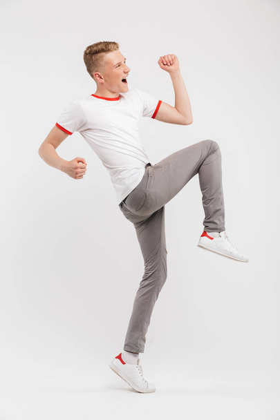 Full length portrait of a cheerful teenage boy celebrating success isolated over white background - Fotoğraf, Görsel
