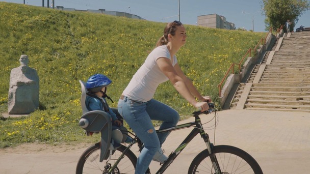 A mãe feliz com o filho está a andar de bicicleta no parque. Movimento lento
 - Filmagem, Vídeo